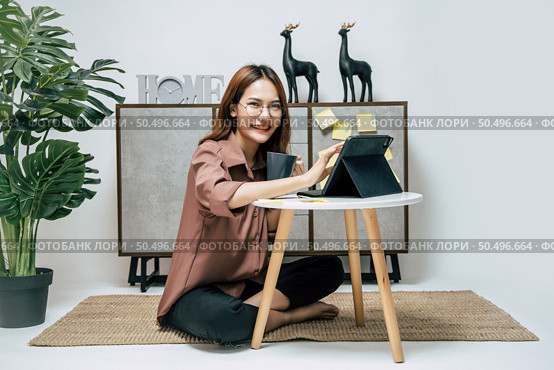 Portrait of smiling happy woman relaxing with coffee, using technology of digital pen on tablet to working from home during self-isolation and quarantine covid-19 coronavirus outbreak. Стоковое фото, агентство Ingram Publishing / Фотобанк Лори