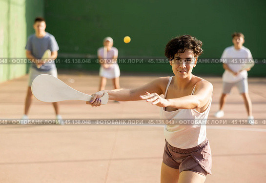Portrait of sporty girl playing paleta fronton on outdoor court, ready to hit ball. Healthy and active lifestyle concept. Стоковое фото, фотограф Яков Филимонов / Фотобанк Лори