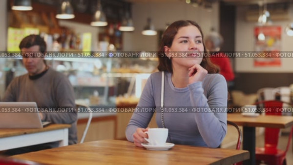 Portrait of young girl with cup in hands drinking coffee in coffee shop indoors. Стоковое видео, видеограф Яков Филимонов / Фотобанк Лори