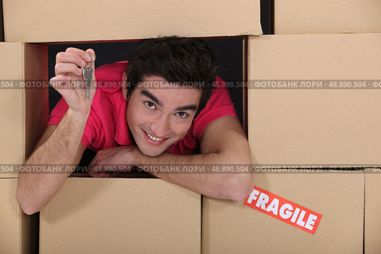 portrait of young man amid removal boxes holding key. Стоковое фото, агентство Ingram Publishing / Фотобанк Лори
