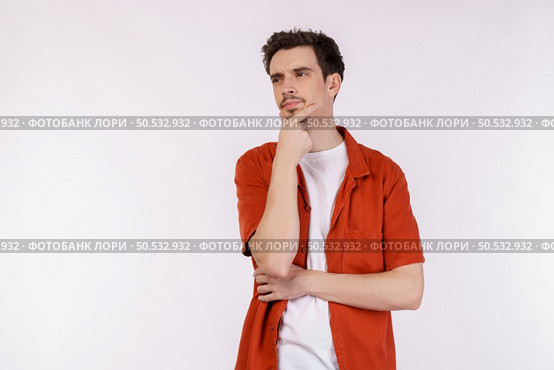 Portrait of young man thinking touching chin isolated over white background. Thinking worried about a question, concerned and nervous with hand on chin. Стоковое фото, агентство Ingram Publishing / Фотобанк Лори