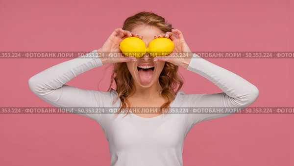 portrait playful woman holding lemons laughs. Стоковое фото, агентство Ingram Publishing / Фотобанк Лори