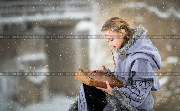 Портрет сказочной эльфийки с волшебной книгой в руках на фоне зимней природы и древней крепости. Стоковое фото, фотограф Мария Мороз / Фотобанк Лори