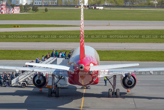 Посадка пассажиров  в самолет Airbus A319-100 (RA-73212) авиакомпании "Россия" на летном поле аэропорта Пулково солнечным майским днем. Санкт-Петербург (2022 год). Редакционное фото, фотограф Виктор Карасев / Фотобанк Лори