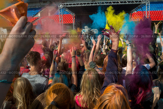 Посетители музыкального фестивале индийских красок ColorFest бросают друг друга сухой краской на конкурном стадионе в Битце города Москвы, Россия (2017 год). Редакционное фото, фотограф Николай Винокуров / Фотобанк Лори
