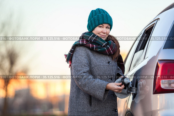 Positive Caucasian female driver portrait with opened gas cap lid of her car, looking at camera. Стоковое фото, фотограф Кекяляйнен Андрей / Фотобанк Лори