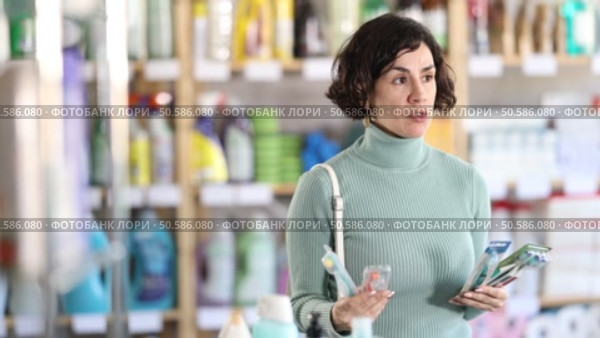 Positive middle-aged female customer choosing convenient toothbrush in large retail store. Стоковое видео, видеограф Яков Филимонов / Фотобанк Лори