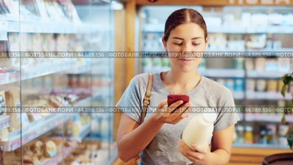 Positive young couple scanning QR code on bottle of milk standing in supermarket with varied stock. Стоковое видео, видеограф Яков Филимонов / Фотобанк Лори
