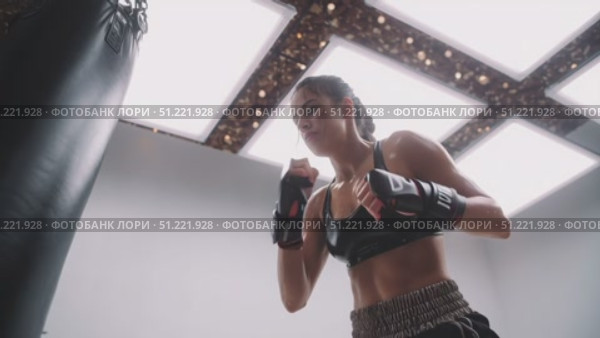 Powerful female athlete practicing boxing punches on a heavy bag, showcasing her strength, skill, and determination in a modern gym setting, illuminated by bright lights. Стоковое AI-видео, аниматор Юрий Поздников / Фотобанк Лори