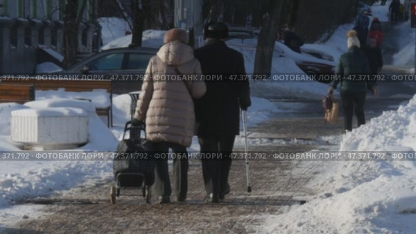Пожилая пара идёт по заснеженному городу. Редакционное видео, видеограф Семён Прудий / Фотобанк Лори