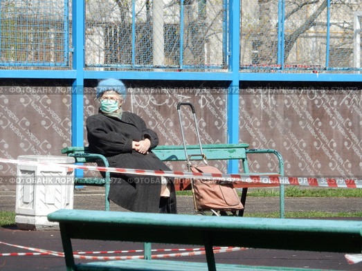 Пожилая женщина в медицинской маске отдыхает на лавочке в дни самоизоляции при коронавирусе COVID-19. Хабаровская улица. Район Гольяново. Город Москва. Россия (2020 год). Редакционное фото, фотограф lana1501 / Фотобанк Лори