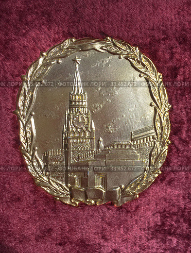 Позолоченная рельефная накладка с изображением Спасской башни Московского Кремля и мавзолея Ленина в лавровом венке на Советском фотоальбоме 40-х годов 20-го века в красном плюше (2019 год). Редакционное фото, фотограф Мария Кылосова / Фотобанк Лори