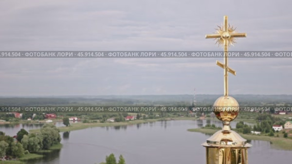 Православный золотой крест над монастырем в Ниловой пустыни  на фоне озера Селигер, берега с домами и облачного неба. Стоковое видео, видеограф Сергей Никифоров-Гордеев / Фотобанк Лори