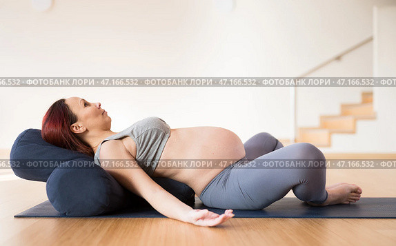 Pregnant woman is engaged in yoga. Reclined Bound Angle Pose or Supta Baddha Konasana. Стоковое фото, фотограф Татьяна Яцевич / Фотобанк Лори