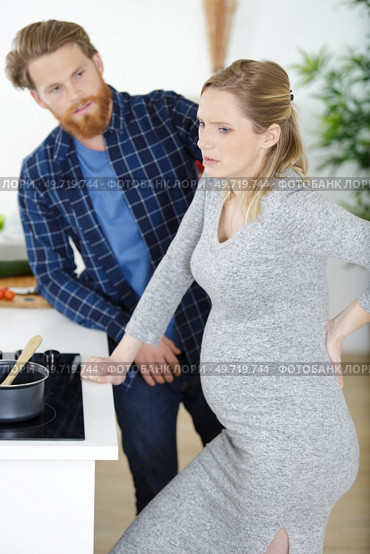 pregnant woman with backache standing in the kitchen. Стоковое фото, агентство Ingram Publishing / Фотобанк Лори