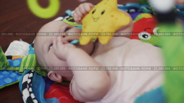 Прелестный ребенок лежит в кроватке, играет с игрушками. Стоковое видео, видеограф Александр Багно / Фотобанк Лори