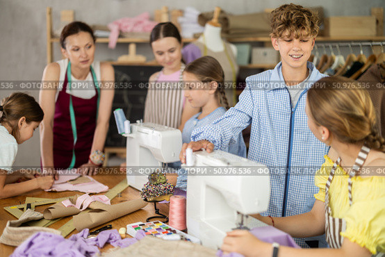 Preteen boy helping classmate thread sewing machine. Стоковое фото, фотограф Яков Филимонов / Фотобанк Лори