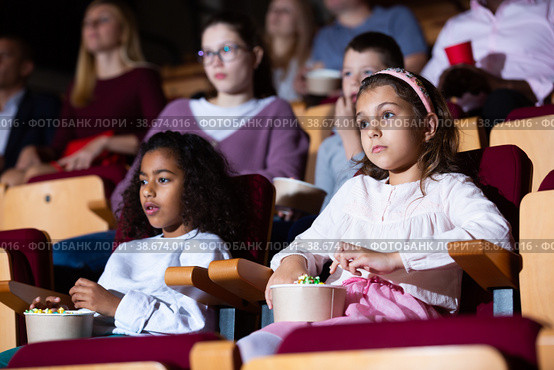 Preteen girl with mulatta mate watching movie in cinema. Стоковое фото, фотограф Яков Филимонов / Фотобанк Лори