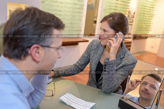 pretty seller helping choosing glasses in optics store. Стоковое фото, агентство Ingram Publishing / Фотобанк Лори