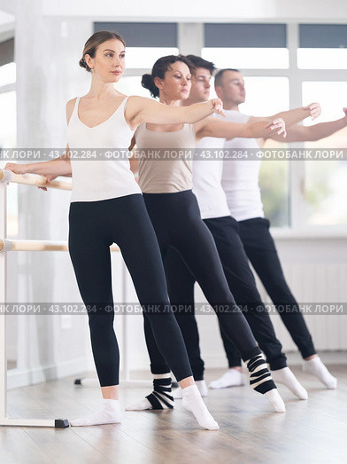 Pretty young girl in black and white sportswear, participating 2nd position of ballet stance at barre with group in choreography studio. Стоковое фото, фотограф Яков Филимонов / Фотобанк Лори