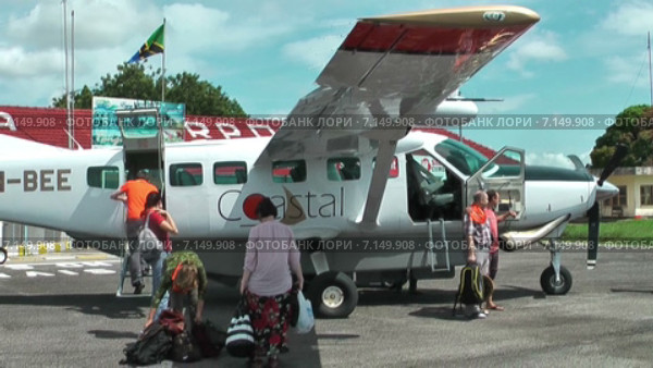 Приземлившийся легкий самолет в международном аэропорту Julius Nyerere Airport (JNIA). Местные авиалинии в Танзании. Пассажиры покидают борт с багажом. Африка (2014 год). Редакционное видео, видеограф Кекяляйнен Андрей / Фотобанк Лори