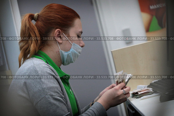 Продавец сотовой связи в защитной маске в дни самоизоляции при коронавирусной инфекции COVID-19 (2020 год). Редакционное фото, фотограф Дмитрий Неумоин / Фотобанк Лори