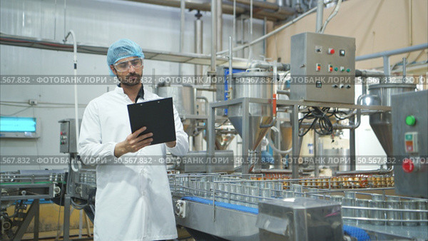 Production control supervisor inspects and controls the operation of each step in the production line of a canned fish factory. Стоковое фото, агентство Ingram Publishing / Фотобанк Лори