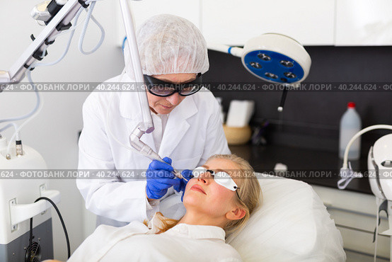 Professional beautician making laser resurfacing to female client face skin. Стоковое фото, фотограф Яков Филимонов / Фотобанк Лори