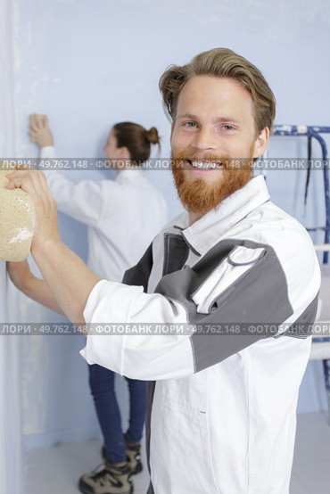 professional man with sponge float plastering white wall. Стоковое фото, агентство Ingram Publishing / Фотобанк Лори