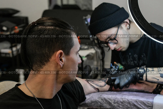 Professional tattoo artist stuffs a tattoo on the man's hand. Tattoo artist at work. Tattoo creation process. Art and creativity. Стоковое фото, фотограф Елена Никишина / Фотобанк Лори