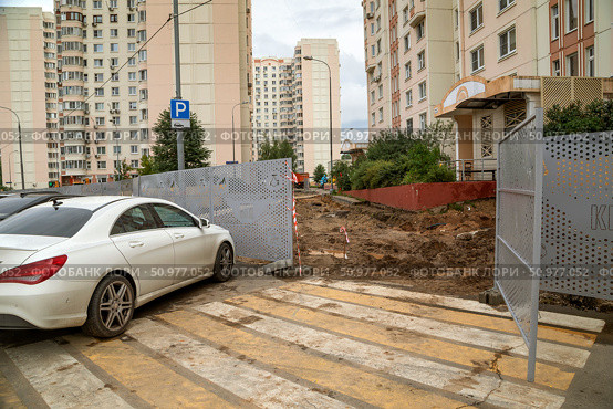 Производство земляных работ с нарушениями в непосредственной близости от жилого дома. Забор раскрыт, и с пешеходного перехода пешеход попадает прямо на строительную площадку. Москва, улица Большая Марфинская. Редакционное фото, фотограф Наталья Николаева / Фотобанк Лори