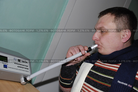 Проверка на алкоголь. Мужчина дует в трубочку алкометра (2009 год). Редакционное фото, фотограф Александр Легкий / Фотобанк Лори