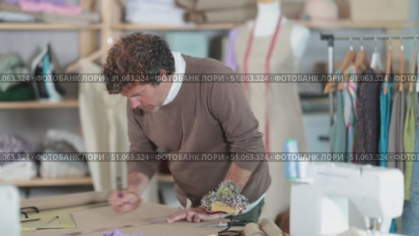 Qualified clothing designer draws a sketch on paper in a sewing workshop. Стоковое видео, видеограф Яков Филимонов / Фотобанк Лори