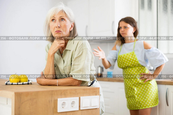 Quarrel of an elderly mother and adult daughter in the kitchen. Adult daughter is unhappy with elderly mother. Стоковое фото, фотограф Яков Филимонов / Фотобанк Лори