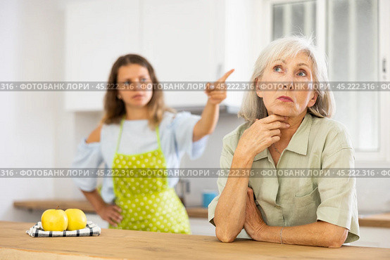 Quarrel of an elderly mother and adult daughter in the kitchen. Adult daughter is unhappy with elderly mother. Стоковое фото, фотограф Яков Филимонов / Фотобанк Лори
