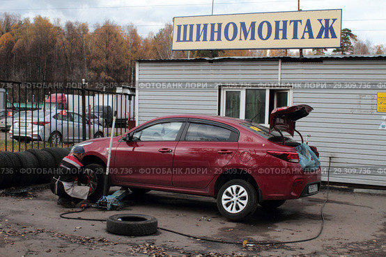 Рабочий шиномонтажа меняет колёса в Балашихе на улице Мира (2018 год). Редакционное фото, фотограф Дмитрий Неумоин / Фотобанк Лори