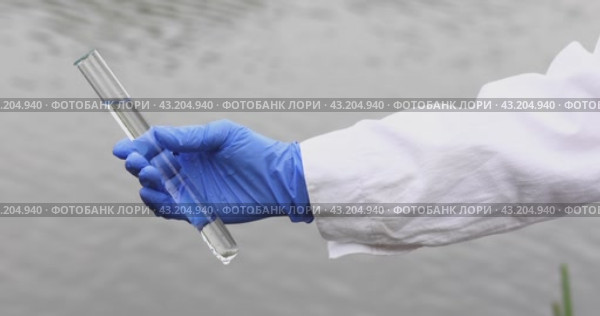 Работник биологической лаборатории держит в руке пробирку с образцами воды из водохранилища для анализа и своевременного выявления опасных для человека бактерий. Стоковое видео, видеограф Сергей Чайко / Фотобанк Лори