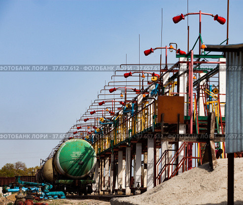 Railway oil tank filling terminal on oil refinery plant in desert. Anti-fire system with extinguishers. Blue sky background. Taraz city. (2012 год). Редакционное фото, фотограф Alexey Rezvykh / Фотобанк Лори