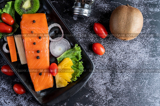 Raw salmon fillets, pepper, kiwi, pineapples, and rosemary onto a plate and black cement floor. Стоковое фото, агентство Ingram Publishing / Фотобанк Лори