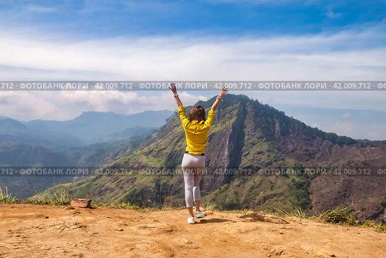 Rear view of lady in yellow jacket arms raised at landmark nature background, Sri Lanka, Ella. Full length of woman enjoy at landscape Adam's peak mountain. Summer vacation concept. Copy ad text space. Стоковое фото, фотограф Aleksandr Golubev / Фотобанк Лори