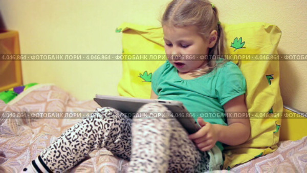 Ребенок с планшетом на кровати. Стоковое видео, видеограф Кекяляйнен Андрей / Фотобанк Лори