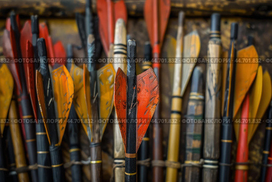 Red and yellow fletching on arrows in a row close up. Стоковое AI-изображение, AI-художник Иван Рябоконь / Фотобанк Лори