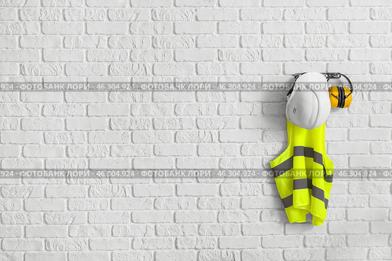 Reflective vest and hearing protectors on white brick wall. Стоковое фото, фотограф Pixel_shot / Фотобанк Лори