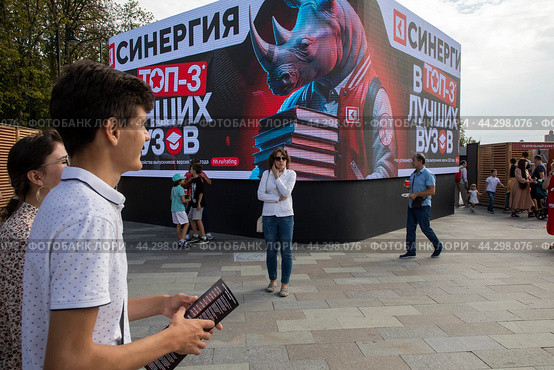 Реклама на огромном экране московского финансово-промышленного университета "Синергия" на площади у здания Северного речного вокзала в городе Москве, Россия (2024 год). Редакционное фото, фотограф Николай Винокуров / Фотобанк Лори