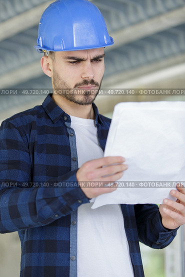 repairman or builder in helmet working with drawings. Стоковое фото, агентство Ingram Publishing / Фотобанк Лори