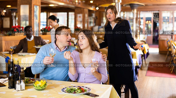 Resentful wife scolding her husband spending time with another woman at dinner. Стоковое фото, фотограф Яков Филимонов / Фотобанк Лори