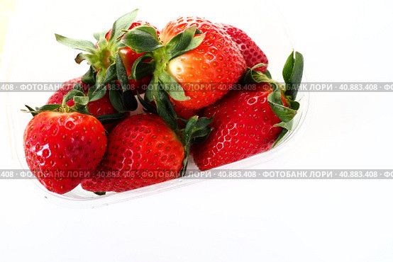Ripe strawberries in a plastic package on a white background. Delicious fresh berries in a container for sale to customers. Keeping food fresh. Healthy food, vitamins and microelements. Стоковое фото, фотограф Юлия Петровская / Фотобанк Лори