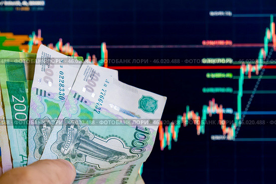 Российские рубли, в частности купюры номиналом 200 и 1000 рублей. На заднем плане виден график с биржевыми котировками изменений цен на фондовом рынке. Стоковое фото, фотограф Valeryi Vysotkov / Фотобанк Лори