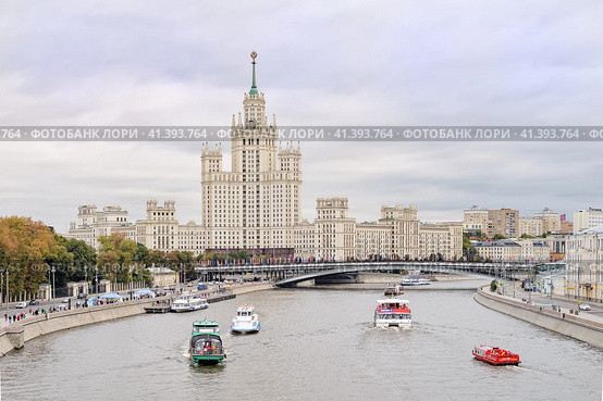 Россия, Москва. Высотное здание на Котельнеческой и Космодемианской набережной. По Москве реке в день города плавают речные трамвайчики и теплоходы. Парад речных судов. (2023 год). Стоковое фото, фотограф Сергей Никифоров-Гордеев / Фотобанк Лори