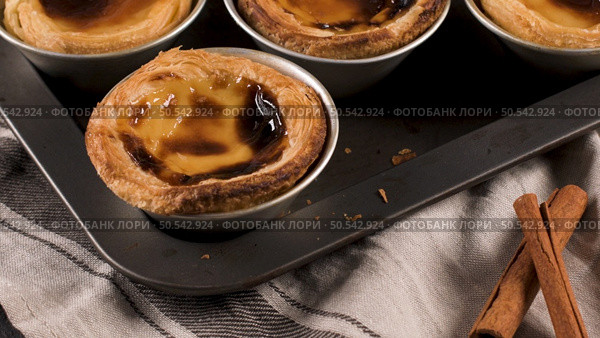 Rows of freshly cooked egg tarts, traditional portuguese dessert, pastel de nata, custard tarts on metal tray. Стоковое фото, агентство Ingram Publishing / Фотобанк Лори
